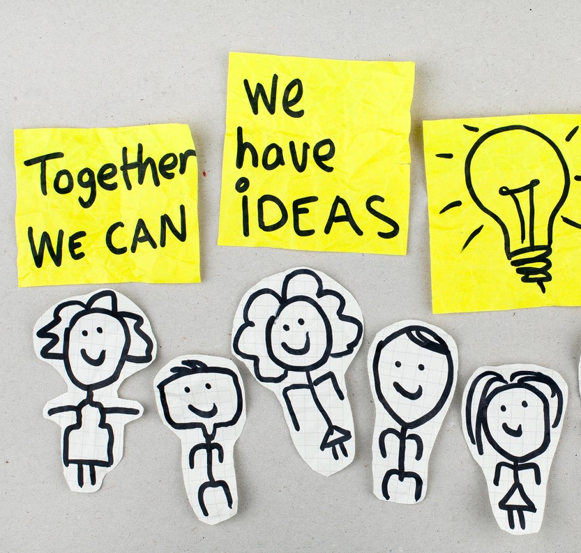 teamwork is more creative. Shows post it notes saying together we can, we have ideas. There's a picture of a lightbulb and a group of people hand drawn with a black marker.
