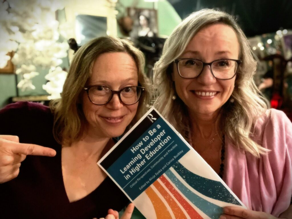 Dr Carina Buckley and Dr Alicja Syska celebrating the publication of their new co-edited book "How to be a Learning Developer in Higher Education".  Alicja is holding a copy of the book and Carina is pointing to the book. 