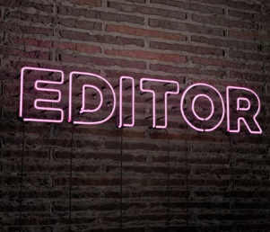 Editor in neon lights lit up on a brick wall.